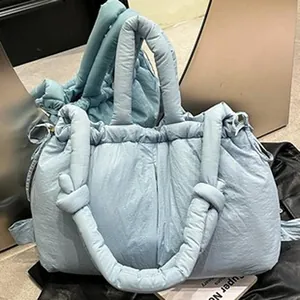 Primer plano de bolso acolchado azul claro con diseño de burbujas y asa suave.