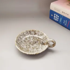 Détail d'un bougeoir moderne en céramique avec glaçure mouchetée et poignée ronde