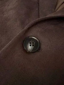 Gros plan détaillé d'un bouton marbré sur une veste de blazer en daim marron vintage