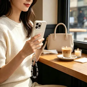 Nahaufnahme einer stylischen schwarz-silbernen Handy-Handgelenkschlaufe im Café-Ambiente