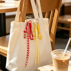 Detailansicht bunter gewebter Taschenanhänger mit Herzverschluss an einer Canvas-Tasche.