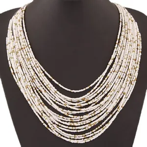 Elegante collana bohémien multistrato di perline bianche e oro su un busto nero