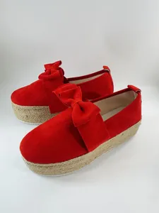 Detailed side view of stylish red suede-like platform shoes with a large decorative bow