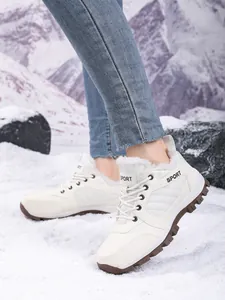 Detail view of women's white high-top fur-lined winter snow boots on snowy ground