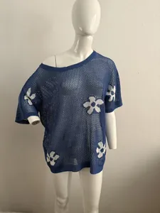 Detailansicht des blauen Oversized-Strickoberteils mit weißen Blumenmustern und Lochmuster.