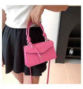 Trendy bright pink pleated handbag with unique knotted handle being carried by model
