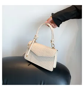 Dettaglio borsa a mano crema chic con texture plissettata e manico annodato elegante