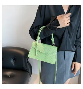 Dettaglio di una piccola borsa quadrata verde lime testurizzata con manico a nodo elegante