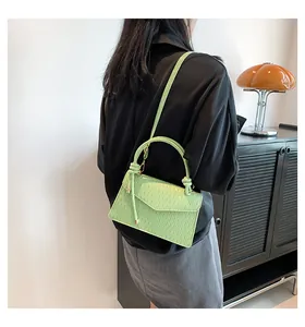 Elegante borsa a tracolla testurizzata verde chiaro con manico indossata da una modella
