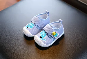Gros plan de chaussures de marche bleues pour bébé avec motif monstre et semelle souple