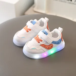 Zapatillas blancas para niños con suelas de luces LED de colores y cordones naranjas