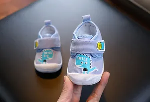 Gros plan d'une chaussure bébé bleue avec motif de dinosaure et inscription SMILE