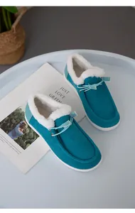 Gemütliche türkisfarbene Cord-Schneestiefel mit weißem Kunstfellfutter auf einem Tablett