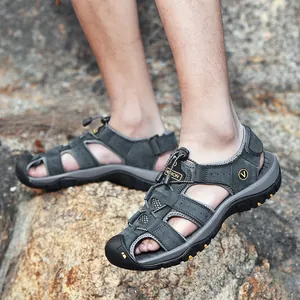 Close-up detail of men's closed-toe leather beach sandals worn on a rocky outdoor surface.