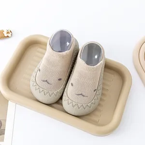 Detailweergave van beige babysokjes met schattig geborduurd gezichtje en zachte zool