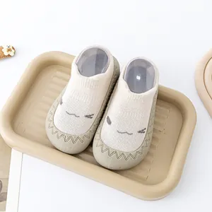 Detailopname van beige babysok-schoenen met een schattige glimlach en rubberen zool.