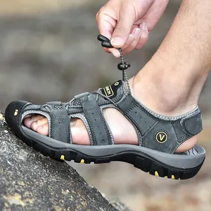 Close-up of men's leather outdoor sandals with elastic laces on a rocky surface.