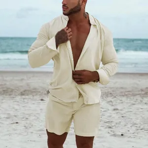 Relaxed men's cream linen long-sleeve shirt and matching shorts set in a beach setting.