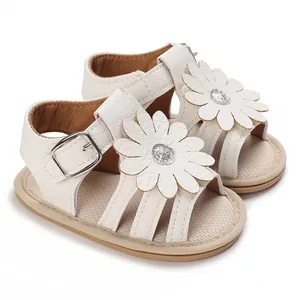 Nahaufnahme weißer Babysandalen mit großer Gänseblümchenblüte und Glitzermitte