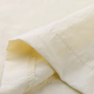 Close-up detail of cream linen fabric showing neat stitching and texture