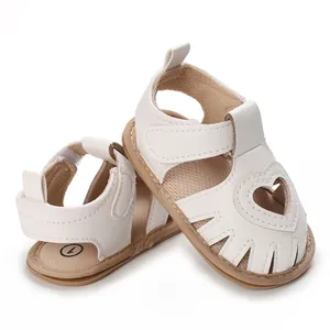 Gros plan de sandales de marche blanches pour bébé avec un joli motif de cœur ajouré