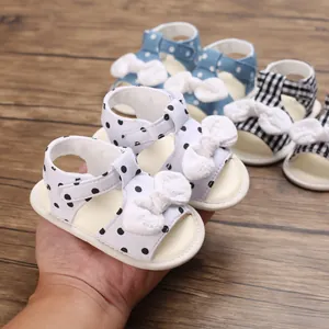 Nahaufnahme von weichen Baby-Sandalen für Mädchen mit süßen Schleifen und Punkten