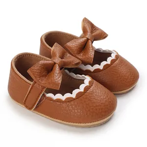 Detailed view of brown infant walker shoes featuring an elegant bow and white scalloped edges