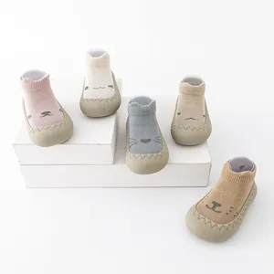 Collectie cartoon babysokschoenen in pastelkleuren op witte houten displayblokken.