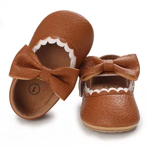 Close-up detail of brown soft-sole baby girl Mary Janes featuring a decorative bow and scalloped trim