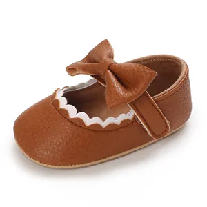 Detailed macro view of brown baby walker shoe with leather bow and scalloped trim