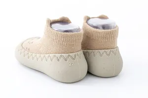 Gedetailleerde weergave van beige babysokschoenen met antislip rubberen zool in maat 22