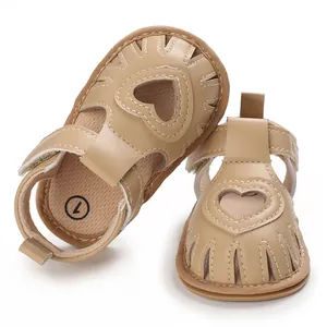 Détail de sandales bébé beiges avec découpes en forme de cœur et semelles souples.