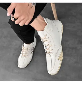 Detailed view of white handmade leather mid-top casual shoes for men with stitching.