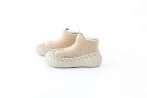 Zijaanzicht van beige baby vloersokken met zachte, antislip rubberen zolen voor grip.