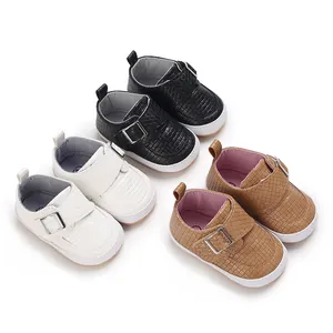 Detailansicht von weichen Baby-Lauflernschuhen in Schwarz, Weiß und Braun mit Webstruktur.