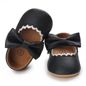 Close-up of black baby princess shoes with leather bow and scalloped trim