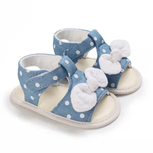 Detailansicht von blauen gepunkteten Babysandalen mit weicher Sohle und weißer Schleife