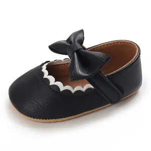 Close-up detail of black faux leather baby girl Mary Jane shoes with bow and scalloped trim