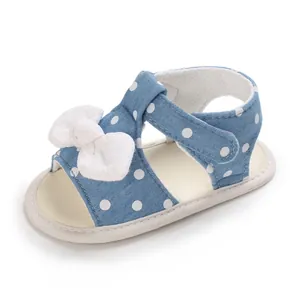 Nahaufnahme einer blauen gepunkteten Babysandale mit weißer Schleife und weicher Sohle