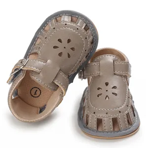 Nahaufnahme von grauen Lauflern-Sandalen für Babys mit weicher Sohle und Blumenmuster