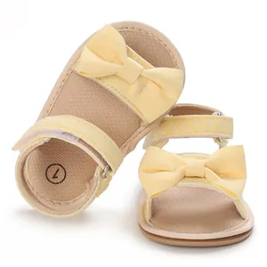 Close-up of yellow baby girl sandals with bow decoration and soft sole for walkers