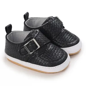 Detail von schwarzen geflochtenen Lauflernschuhen mit weichen weißen Gummisohlen