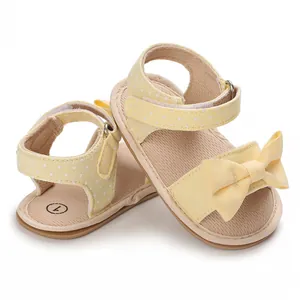 Close-up detail of yellow polka dot baby sandals featuring a soft bow decoration for girls