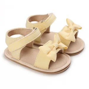 Detailed macro view of yellow baby sandals featuring a large bow and polka-dot straps