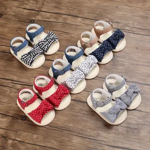 Collezione di adorabili sandali con fiocco per neonata su uno sfondo in legno rustico