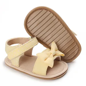 Detailed side view and sole of yellow baby summer sandals with cute bow and polka dots