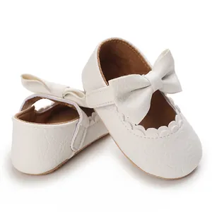 Detail view of white soft-sole baby walking shoes with elegant bow and scallop trim