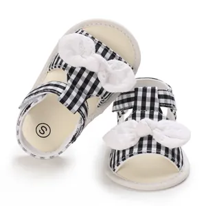 Detailansicht von Baby-Sommersandalen mit Karomuster und weißer Spitzenschleife