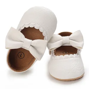 Close-up of elegant white baby princess shoes featuring large bow and scalloped trim