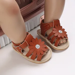 Nahaufnahme stilvoller brauner Babyschuhe für Mädchen mit Blumendekor und Gummisohle.